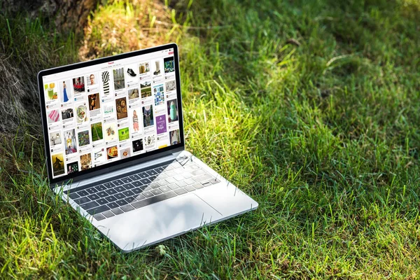 Vista de cerca de la computadora portátil con pinterest sitio web en la hierba al aire libre - foto de stock