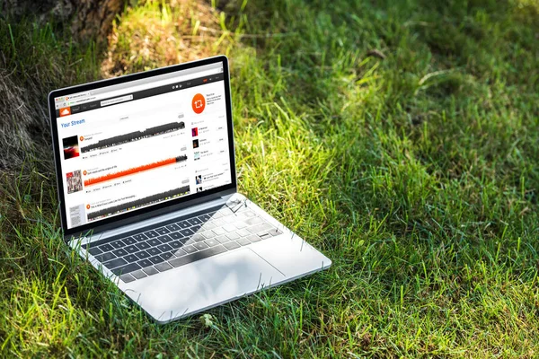 Vista de cerca de la computadora portátil con sitio web soundcloud en la hierba al aire libre - foto de stock