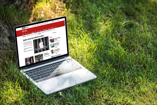 Vista de cerca de la computadora portátil con BBC sitio web de noticias en la hierba al aire libre - foto de stock