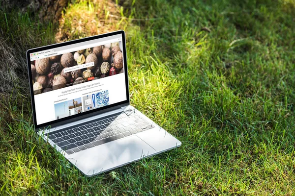 Vista de perto do laptop com site depositphotos.com na grama ao ar livre — Fotografia de Stock