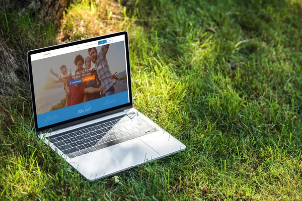 Vue rapprochée de l'ordinateur portable avec site de couchsurfing sur l'herbe à l'extérieur — Photo de stock