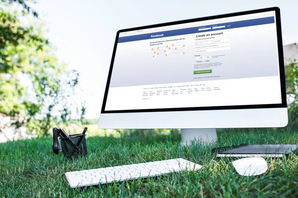 Selektiver Fokus von Lehrbuch und Computer mit Facebook-Website auf Gras im Freien — Stockfoto