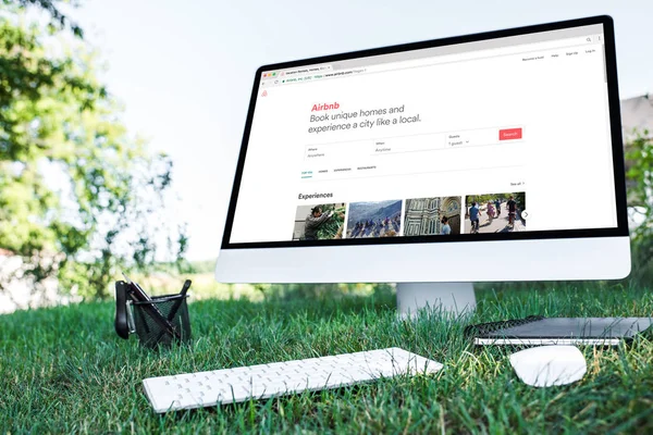 Selektiver Fokus von Lehrbuch und Computer mit Airbnb-Website auf Gras im Freien — Stockfoto