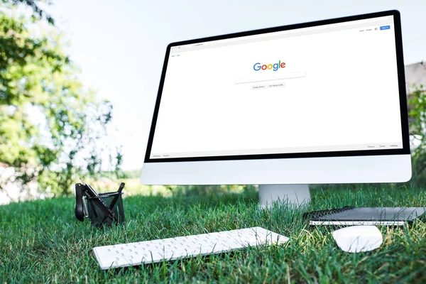 Selective focus of textbook and computer with google website on grass outdoors — Stock Photo