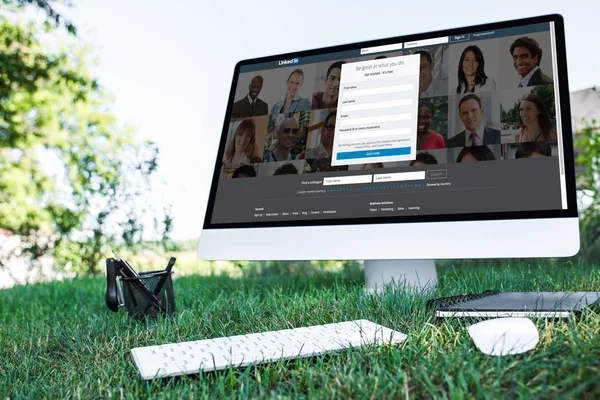 Selective focus of textbook and computer with linkedin website on grass outdoors — Stock Photo
