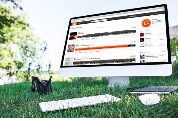 Selective focus of textbook and computer with soundcloud website on grass outdoors — Stock Photo