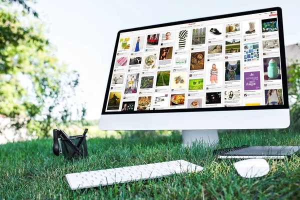 Foyer sélectif du manuel et de l'ordinateur avec le site Web de pinterest sur l'herbe à l'extérieur — Photo de stock