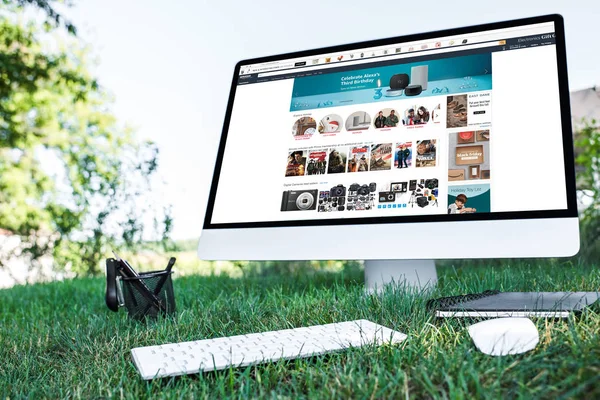 Selective focus of textbook and computer with amazon website on grass outdoors — Stock Photo