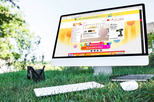 Selective focus of textbook and computer with aliexpress website on grass outdoors — Stock Photo