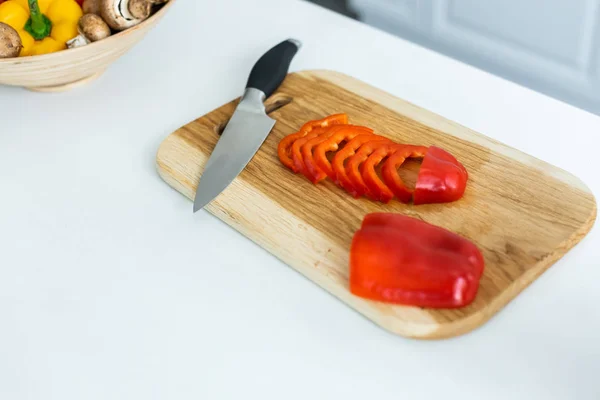 Vista de ángulo alto de pimiento en rodajas y cuchillo en tabla de cortar de madera - foto de stock