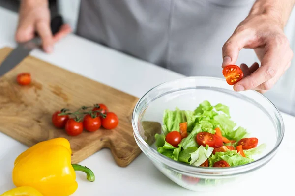 Plan recadré de l'homme en tablier cuisine salade de légumes — Photo de stock
