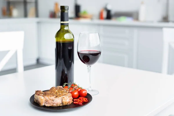 Delicioso filete a la parrilla con verduras en el plato y vino tinto en la mesa - foto de stock