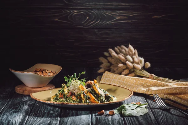 Composición de alimentos de panikesh con espinacas y tazón con nueces de anacardo en mesa de madera - foto de stock