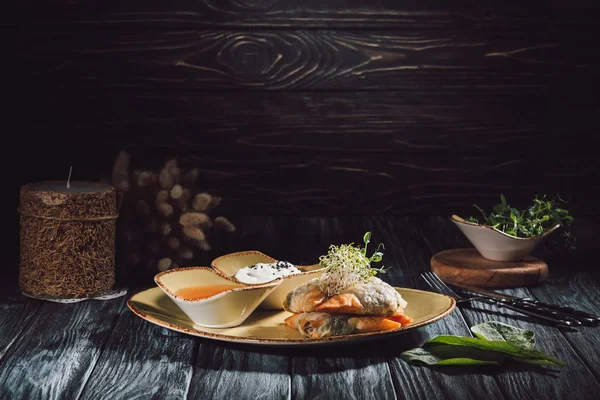 Composizione alimentare di candele e samosa in pasta filata farcita con spinaci e paneer decorata con semi germinati di erba medica e girasole su piatto con salse — Foto stock