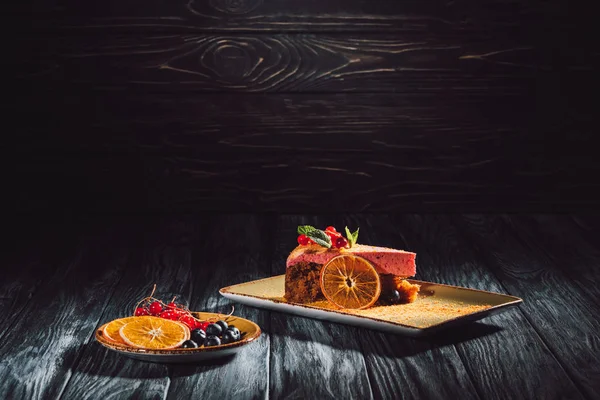 Морковный пирог с ягодной начинкой и оранжевыми ломтиками, черникой и клюквой на блюдце — стоковое фото