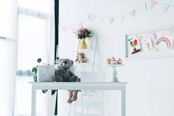 Décoré pour la chambre d'anniversaire avec ours en peluche, boîte cadeau et cupcakes sur la table — Photo de stock