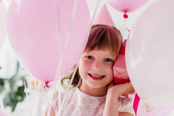 Portrait of happy birthday child in cone holding gift box and air balloons — Stock Photo