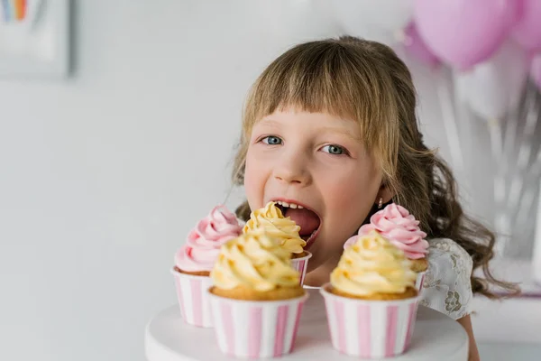 Close up portrait of adorable birthday child eating cupcakes — Stock Photo