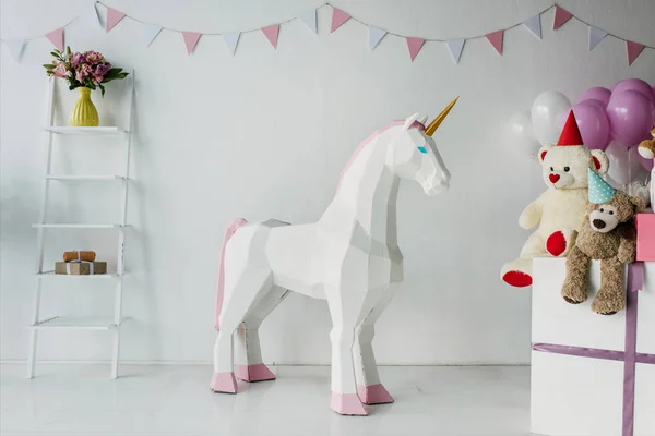 Unicornio decorativo, osos de peluche en conos y globos de aire en decorado para sala de cumpleaños - foto de stock