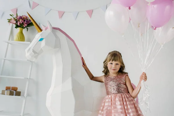Entzückendes kleines Kind mit Luftballons und dekorativem Einhorn — Stockfoto