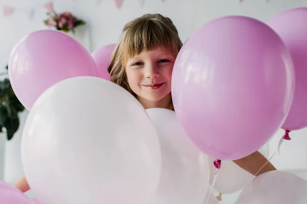 Retrato de niño adorable sonriente de pie con globos de aire - foto de stock