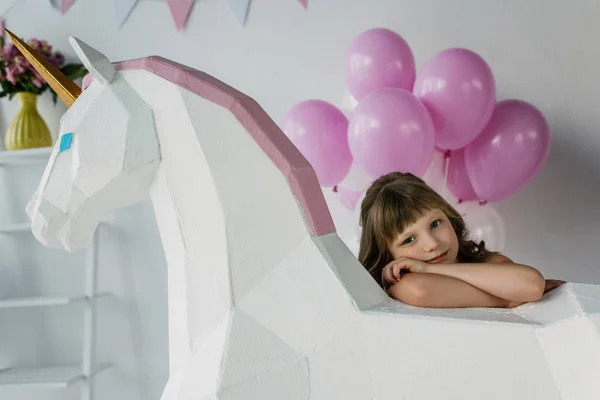 Little child sitting with decorative unicorn and bunch of pink balloons — Stock Photo