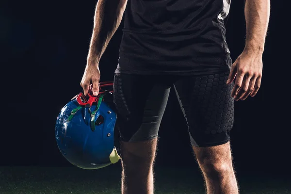 Schnappschuss eines amerikanischen Fußballspielers mit Helm in der Hand auf schwarz — Stockfoto