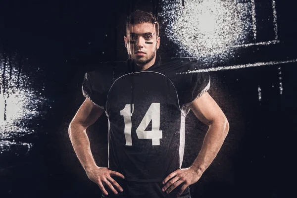 Vista del giocatore di football americano guardando la fotocamera sul nero attraverso il vetro bagnato — Foto stock