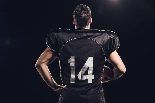 Rückansicht eines amerikanischen Fußballspielers mit Helm in der Hand isoliert auf schwarz — Stockfoto