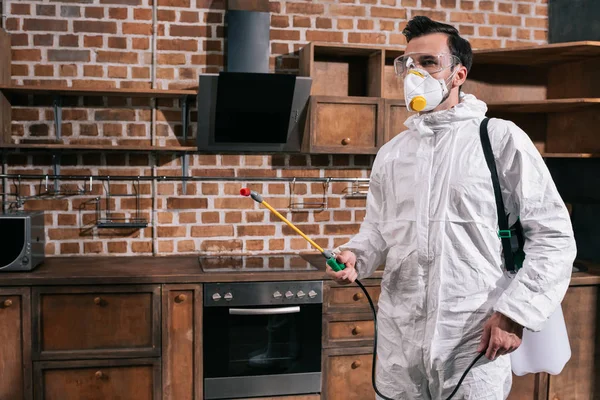 Side view of pest control worker standing with sprayer in kitchen — Stock Photo