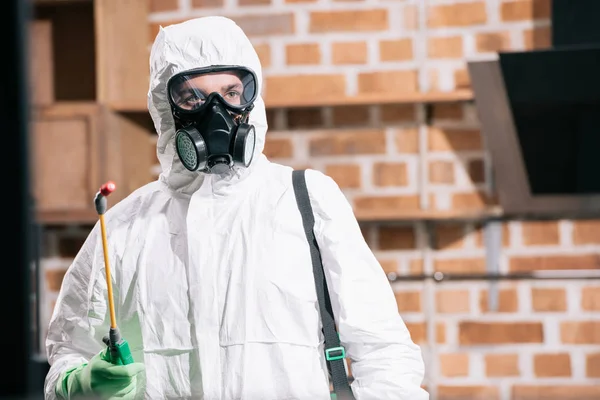 Pest control worker standing with sprayer in kitchen and looking away — Stock Photo