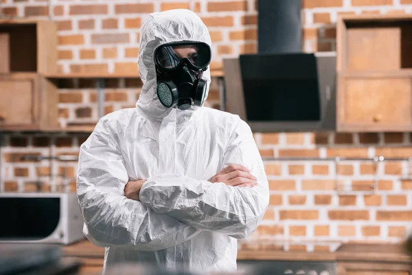 Trabajador de control de plagas de pie en uniforme con brazos cruzados en la cocina - foto de stock