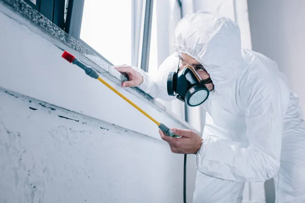 Travailleur de la lutte antiparasitaire pulvérisation de pesticides sous le rebord de la fenêtre à la maison — Photo de stock