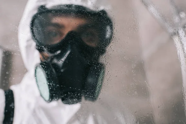 Trabajador de control de plagas de pie en el respirador en el baño y mirando a la cámara - foto de stock