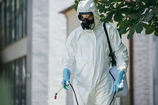 Pest control worker spraying pesticides on street with sprayer — Stock Photo