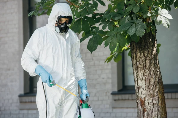 Trabajador de control de plagas rociando pesticidas en la calle - foto de stock