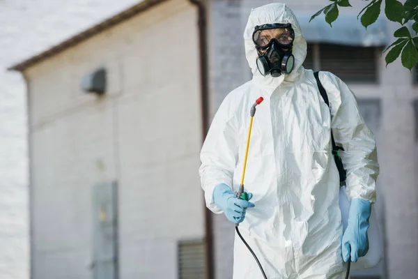 Pest control worker in respirator holding sprayer — Stock Photo