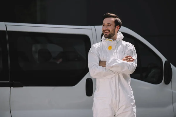 Sorrindo pragas trabalhador de controle em uniforme de pé com os braços cruzados perto do carro na rua — Fotografia de Stock