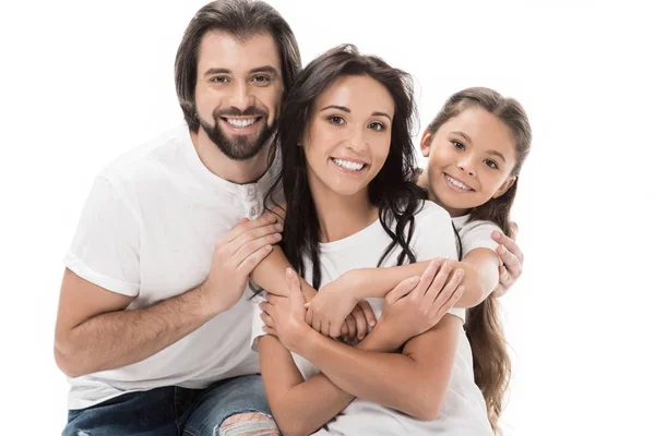 Porträt einer fröhlichen Familie in weißen Hemden, die sich umarmt und vereinzelt in die Kamera schaut — Stockfoto