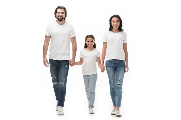 Lächelnde Familie in weißen Hemden und Jeans, Händchen haltend, während sie isoliert auf weißem Grund zusammen geht — Stockfoto