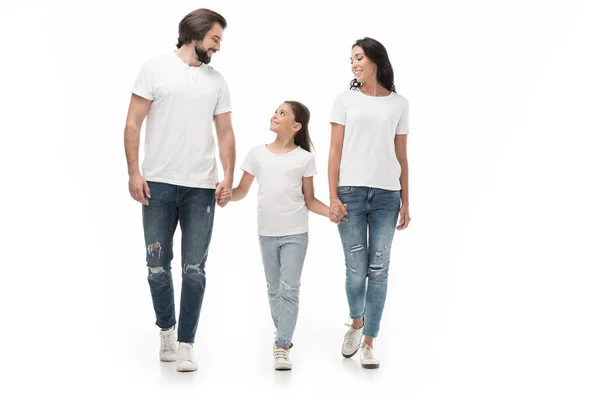 Lächelnde Familie in weißen Hemden und Jeans, Händchen haltend, während sie isoliert auf weißem Grund zusammen geht — Stockfoto