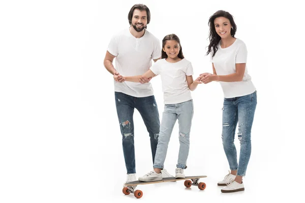 Padres sonrientes ayudando a su hija a patinar en monopatín aislado en blanco - foto de stock