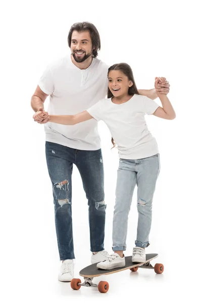 Батько допомагає маленькій доньці кататися на скейті ізольовано на білому — стокове фото