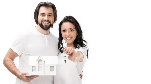 Portrait de couple souriant avec modèle de maison et clés isolées sur blanc — Photo de stock