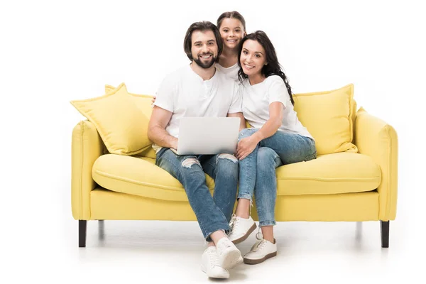 Lächelnde Familie mit Laptop sitzt auf gelbem Sofa isoliert auf weißem Hintergrund — Stockfoto