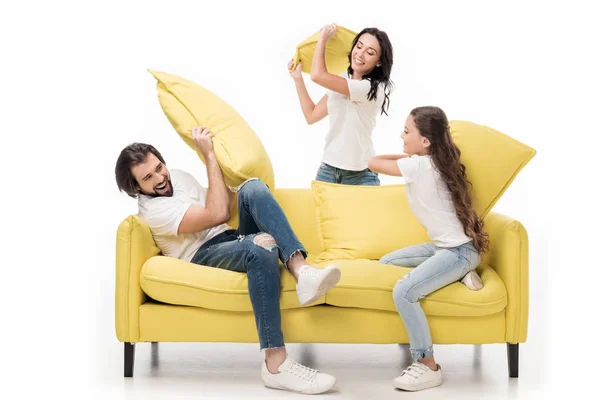 Felice famiglia in camicie bianche su divano giallo avendo lotta cuscino isolato su bianco — Foto stock