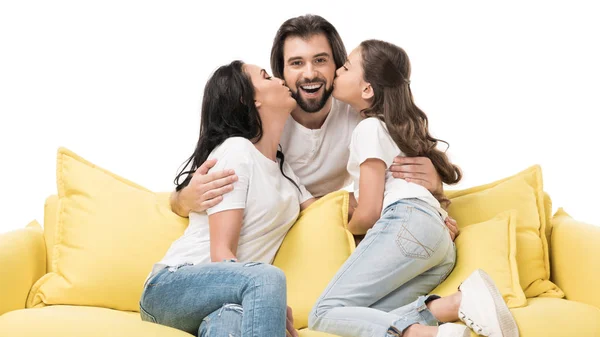 Ritratto di madre e figlia su divano giallo baciare felice padre isolato su bianco — Foto stock