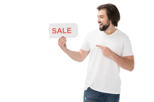 Smiling bearded man pointing at sale banner in hand isolated on white — Stock Photo