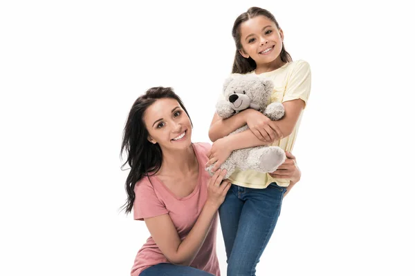 Portrait of smiling mother and little daughter with teddy bear looking at camera isolated on white — Stock Photo