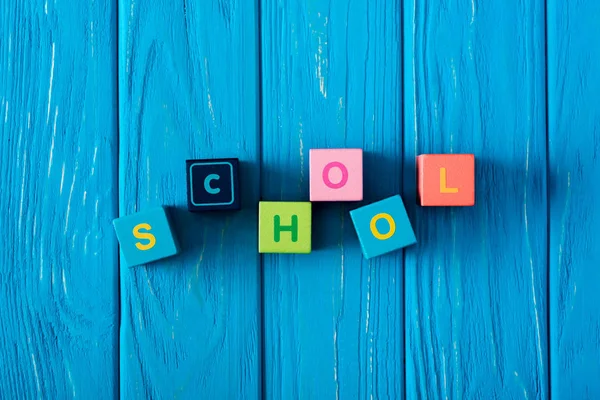 Vista dall'alto della scuola di lettering fatta da cubi su sfondo di legno blu — Foto stock